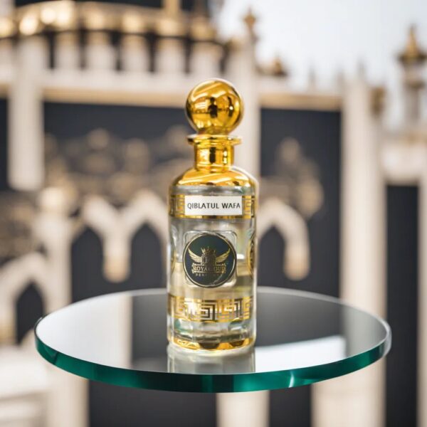 a gold perfume oil bottle sitting on a round glass platform in front of an Islamic background